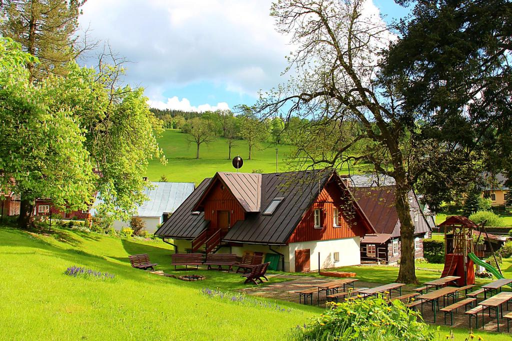 une grange avec un toit noir sur un champ vert dans l'établissement Apartmány mlýn, à Rokytnice nad Jizerou