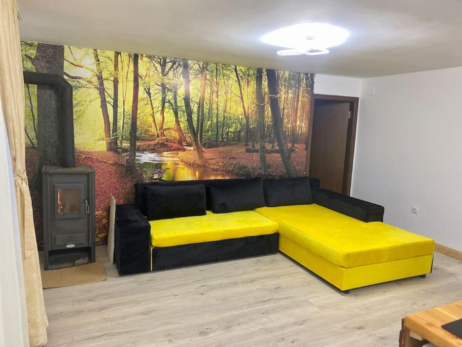 una sala de estar con un sofá amarillo y una pintura en Apartament C&C en Voineasa