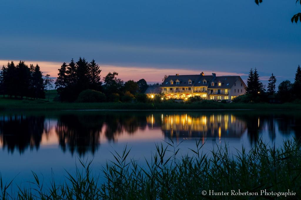 une maison sur la rive d'un lac la nuit dans l'établissement Hotel Lou Granva, à Grande-Rivière