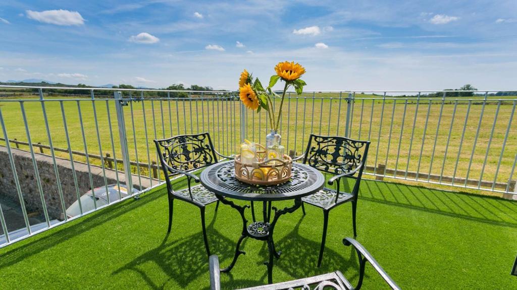 a table with a vase of flowers on a balcony at Ty Gwair in Pentraeth