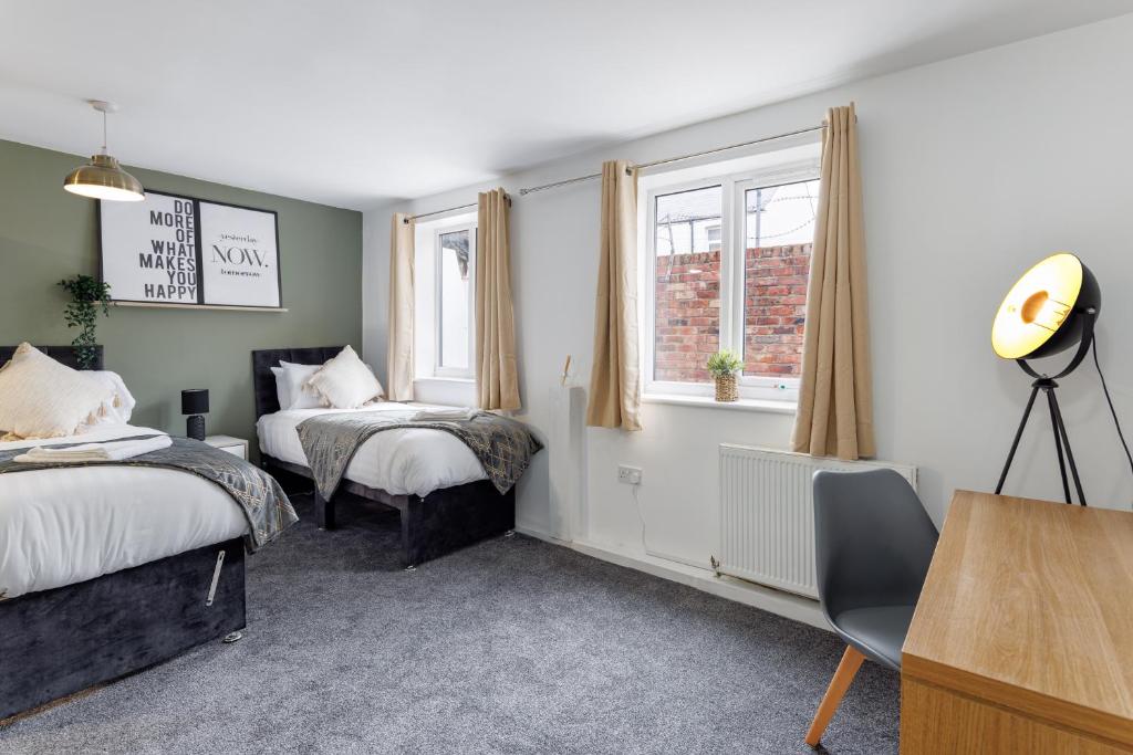 a bedroom with two beds and a desk and two windows at City Centre Studio 3 with Kitchenette, Free Wifi and Smart TV with Netflix by Yoko Property in Middlesbrough