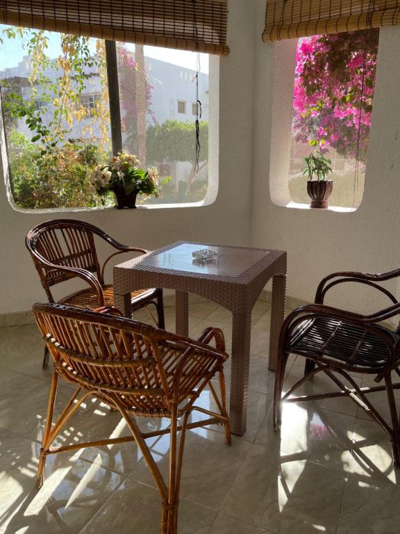 einen Tisch und Stühle in einem Zimmer mit Fenstern in der Unterkunft City Center Apartment 2 - Delta Sharm in Sharm El Sheikh