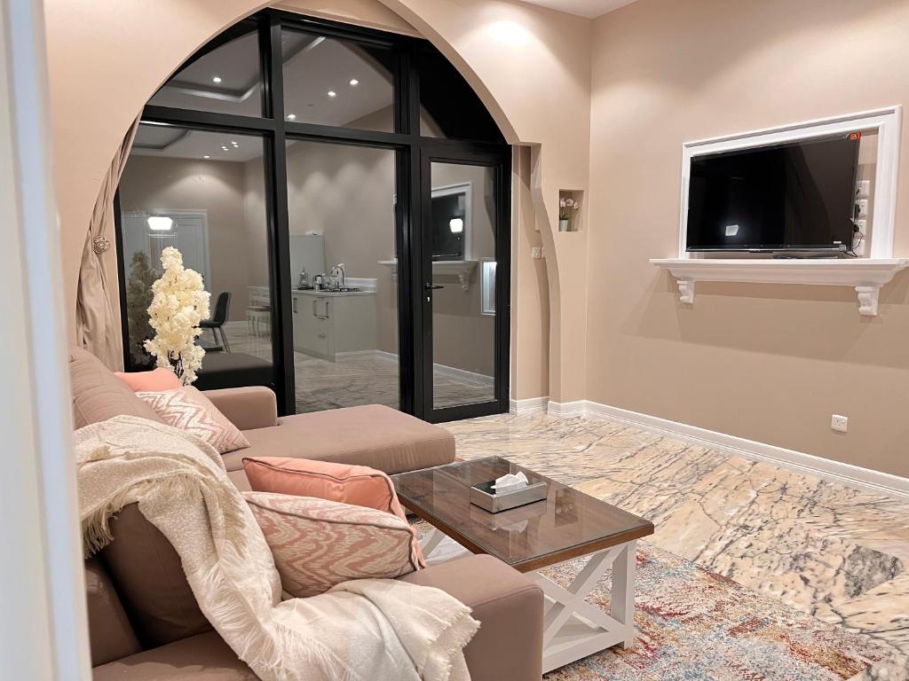 ein Wohnzimmer mit einem Sofa und einem TV in der Unterkunft الأجنحة الرخامية فندقية in Buraida
