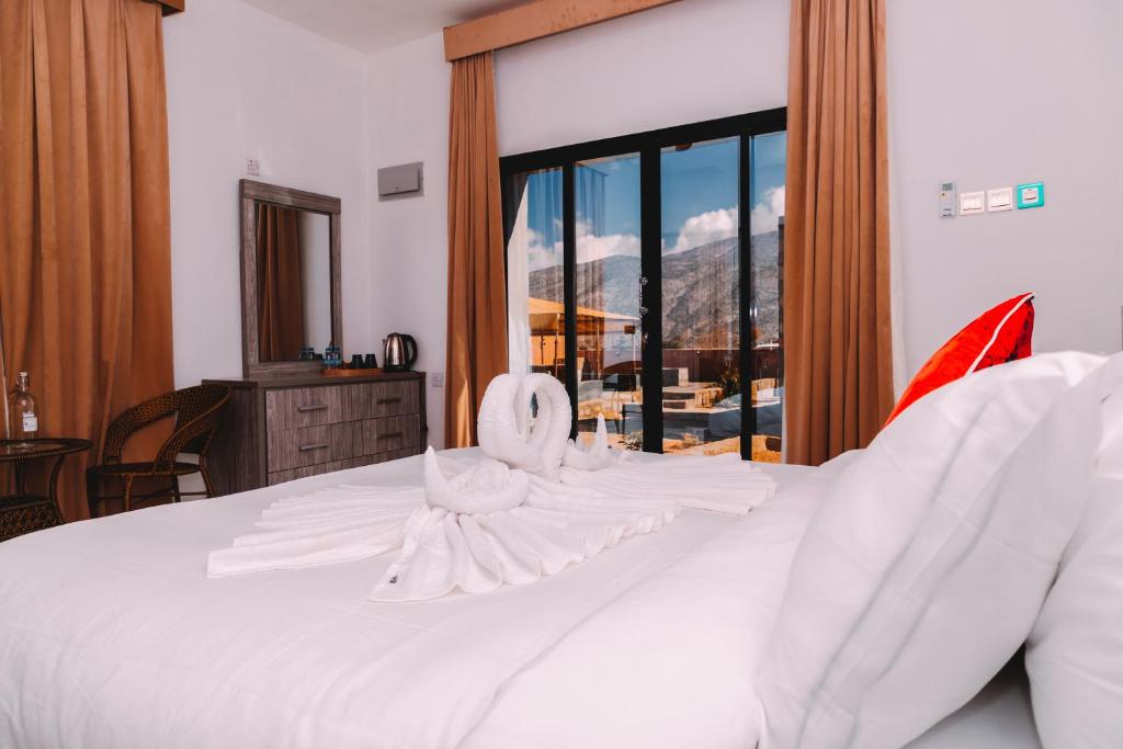 een slaapkamer met een wit bed en uitzicht op de bergen bij MountSun Stay Jabal Shams in Sa‘ab Banī Khamīs