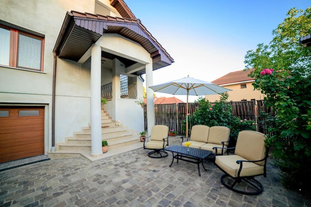 - une terrasse avec 2 chaises, une table et un parasol dans l'établissement Vila centrala Băile Felix, à Băile Felix