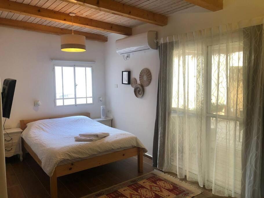een slaapkamer met een bed en een groot raam bij Beautiful Dead Sea Unit in Ovnat