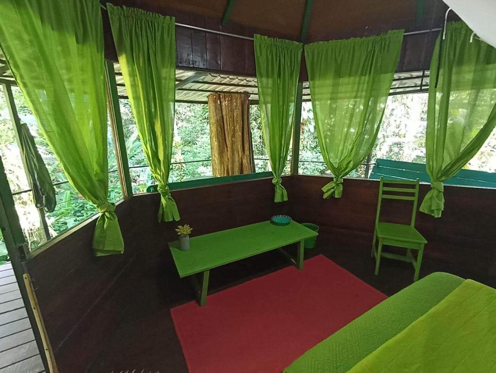 コクレスにあるFinca Valeria Treehouses Glampingの緑のカーテンと緑のテーブルが備わる部屋