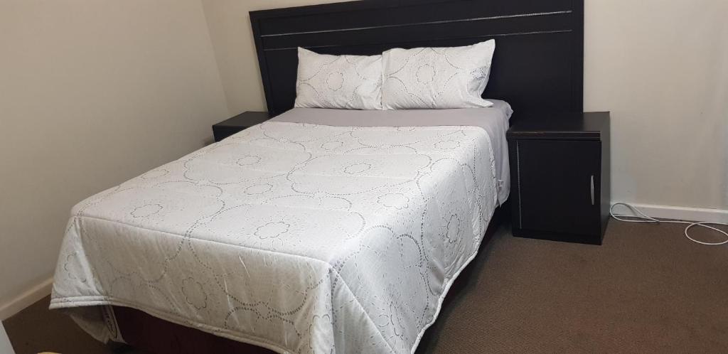 a bedroom with a bed with a white comforter and pillows at Neat Haven Self Catering in Grahamstown