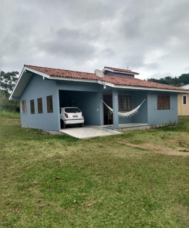 una casa azul con un coche aparcado delante de ella en Casa de 2 Quartos na Praia da Joaquina, en Florianópolis