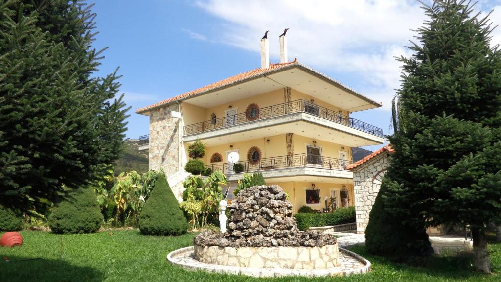 a large yellow house with a fountain in front of it at VALIA ROOMS in Kalavrita