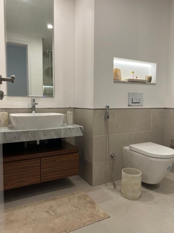 ein Badezimmer mit einem Waschbecken, einem WC und einem Spiegel in der Unterkunft MJL Rahaal2- 301Apartament in Dubai