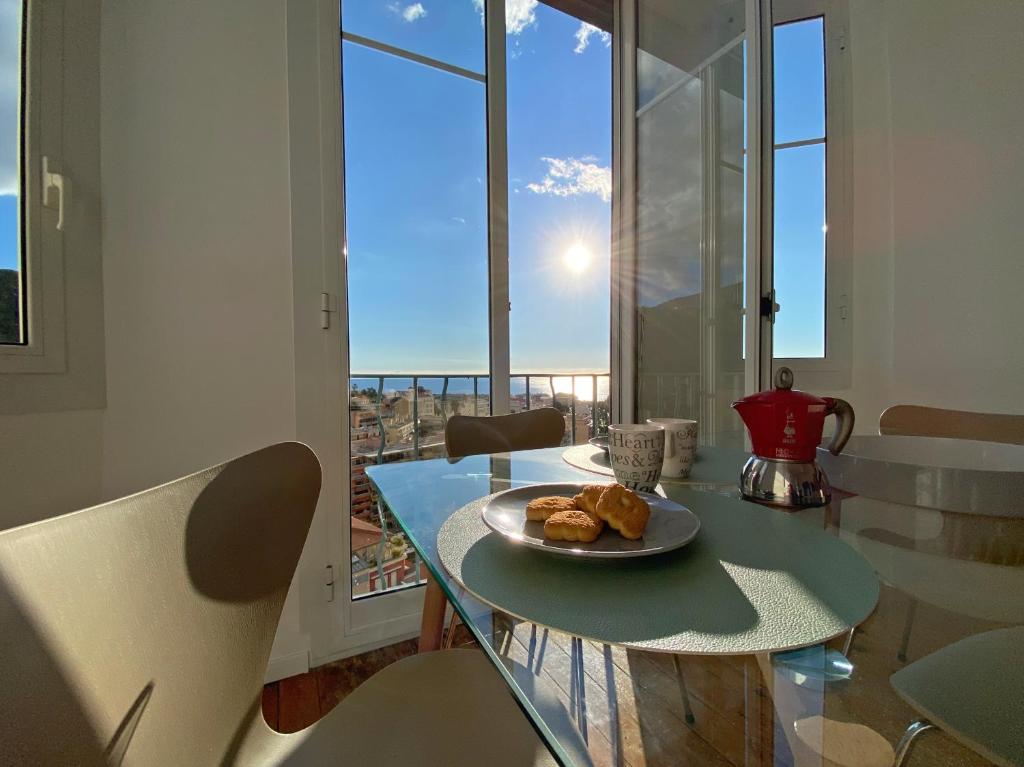 einen Tisch mit einem Teller Essen drauf in einem Zimmer mit Fenstern in der Unterkunft Lutetia Palace Côte d'Azur in Menton
