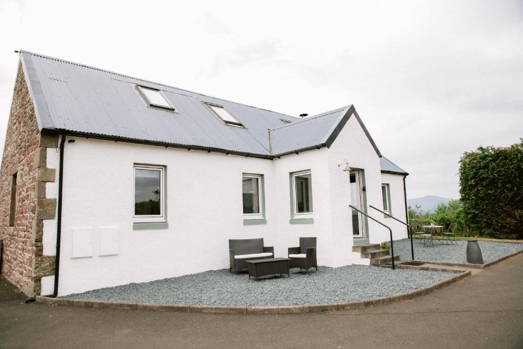 ein weißes Haus mit einem Tisch und Stühlen auf Kies in der Unterkunft Dunruadh Cottage in Gartocharn