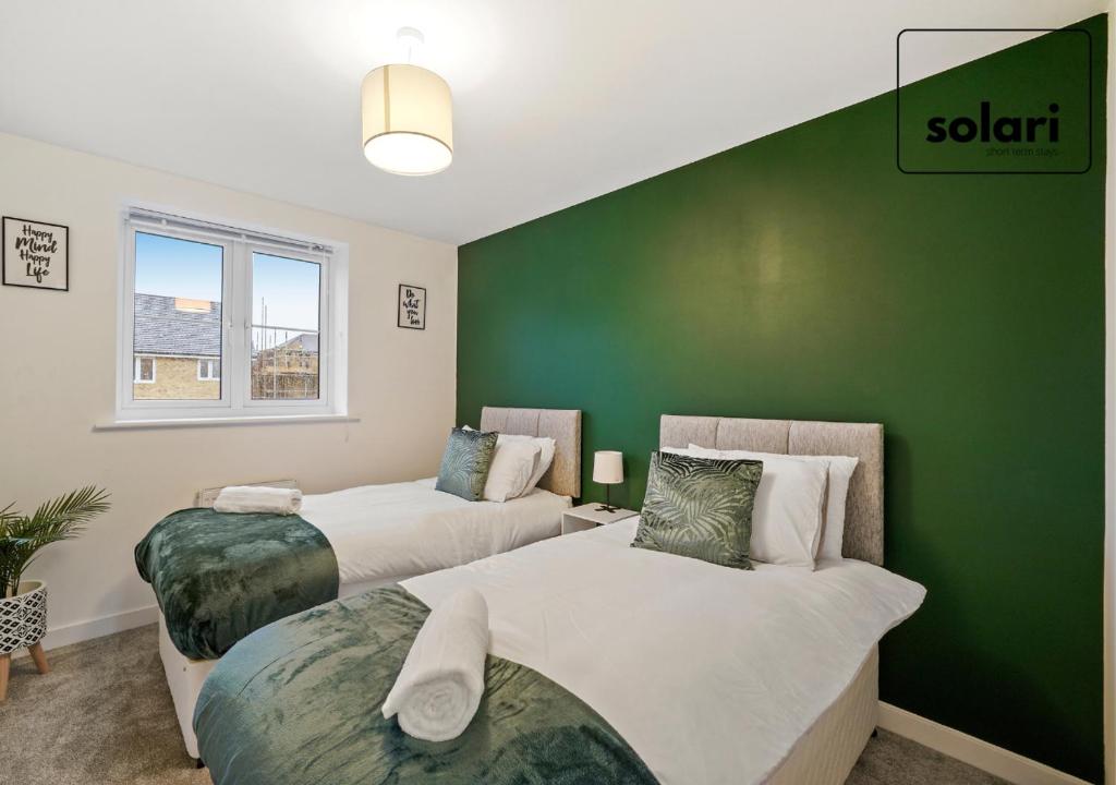 two beds in a room with a green wall at Lux 4 Bed Contractor x Relocator Apartment, 30 Percent Off Monthly Stays, FREE Multiple Parking Spaces, Super Fast WiFi, Streaming Services included, Close to A1 in Peterborough