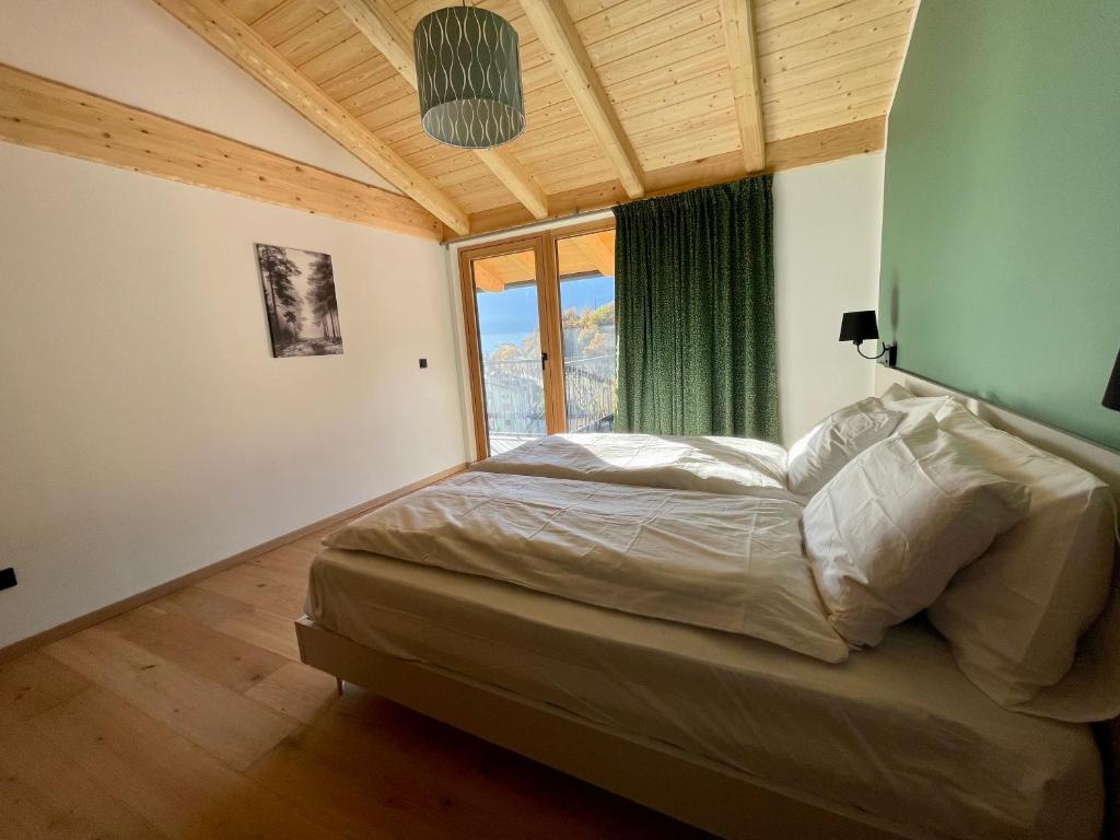 a bedroom with a bed and a large window at La casina di Vigo in Ton