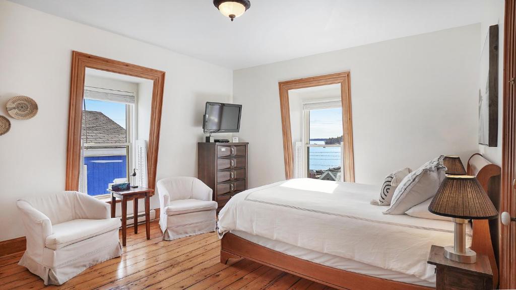 a bedroom with a bed and two chairs and a television at Sail Inn Lunenburg in Lunenburg