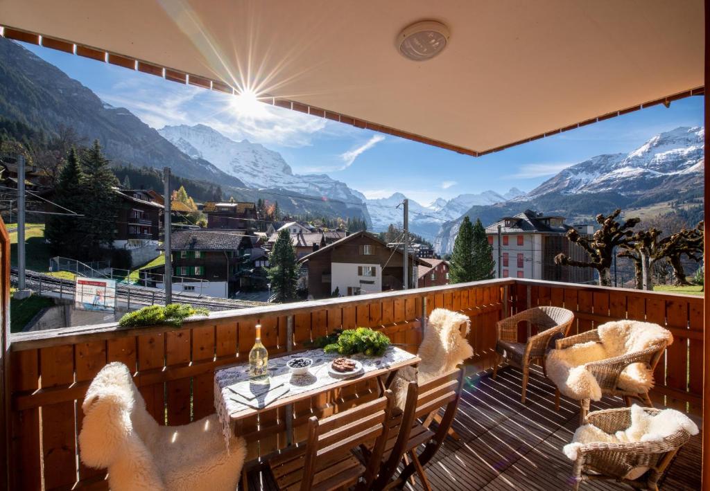 a balcony with a table and chairs and a view of mountains at Chalet Stella Alpina in Wengen