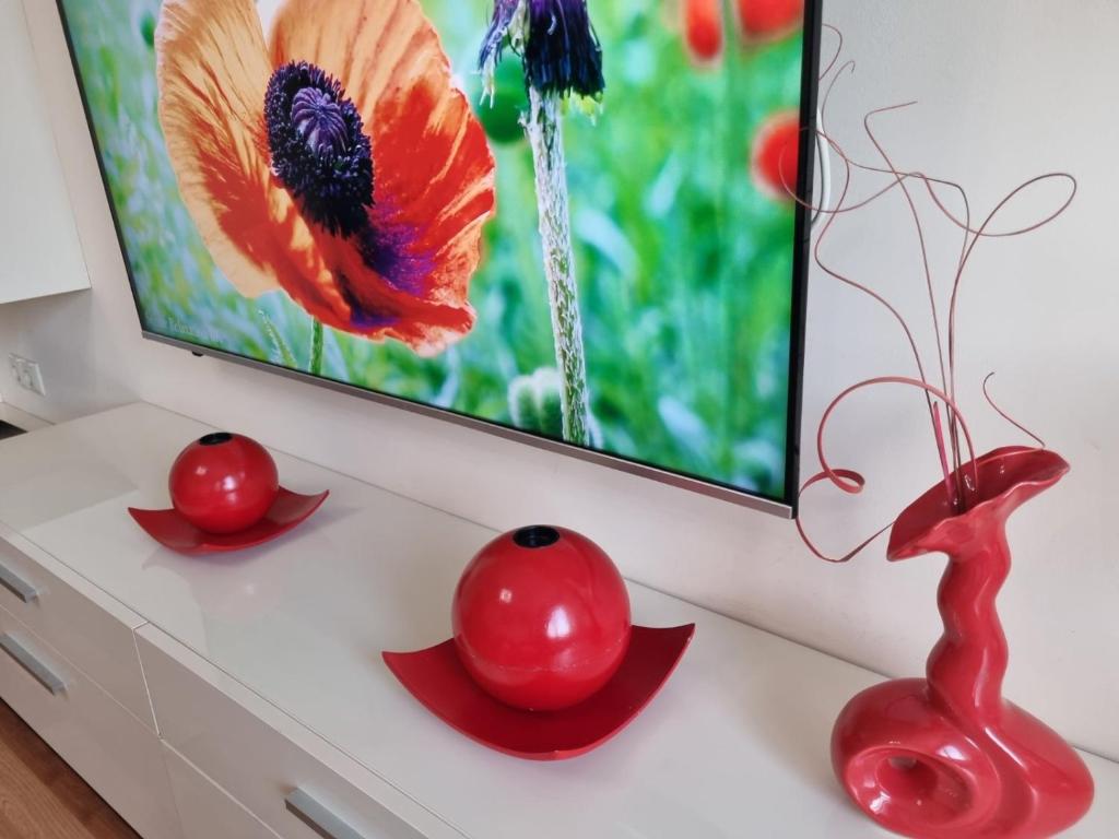 two red vases and two cherries on a dresser at Danube Park in Ruse