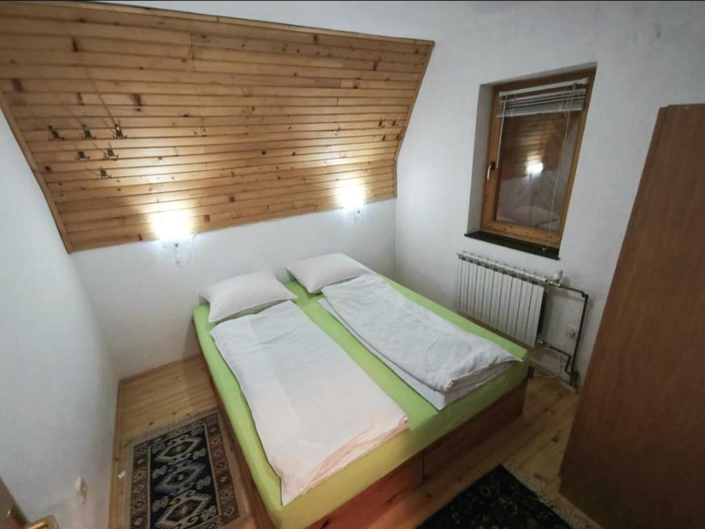 a small bedroom with a bed with a wooden headboard at Apartments A Vlasic in Vlasic