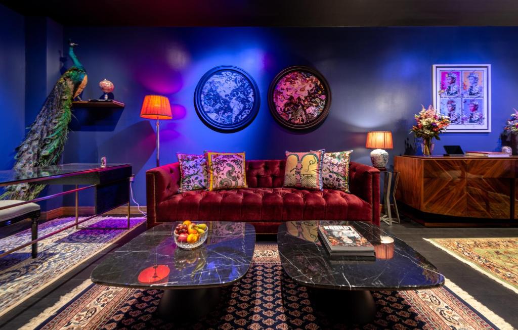 a living room with a red couch and a blue wall at Hux Hotel, Kensington in London