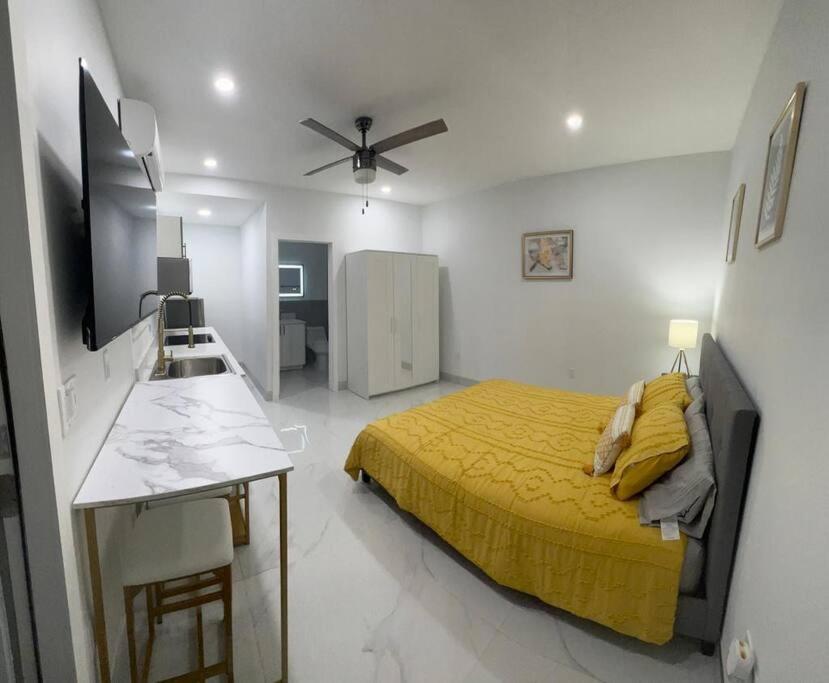 a bedroom with a yellow bed and a kitchen at Stunning Deluxe Studio in Hialeah