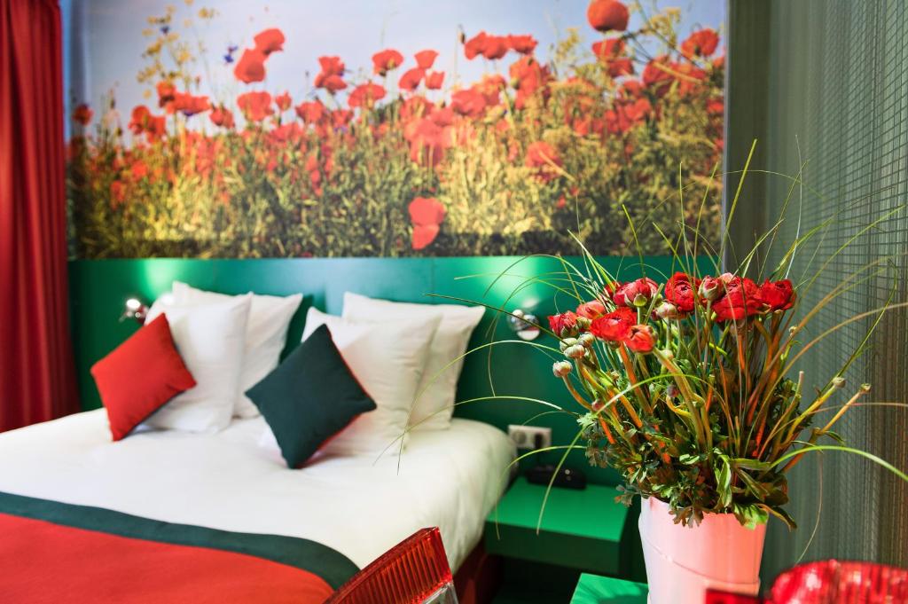 ein Schlafzimmer mit einem Bett und einem Gemälde von roten Blumen in der Unterkunft Jardins de Montmartre in Paris