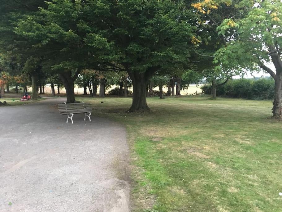 un parque con un banco, árboles y césped en Spacious Countryside/Suburban Retreat-Warwickshire en Walsgrave on Sowe