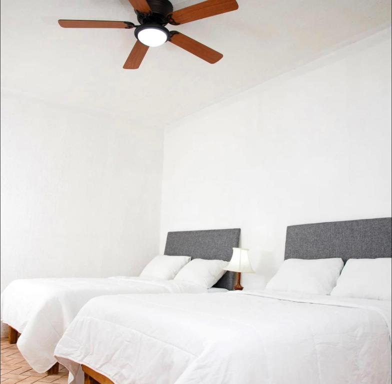 two beds in a white room with a ceiling fan at VILLAS MARQUIS in Ciudad Valles