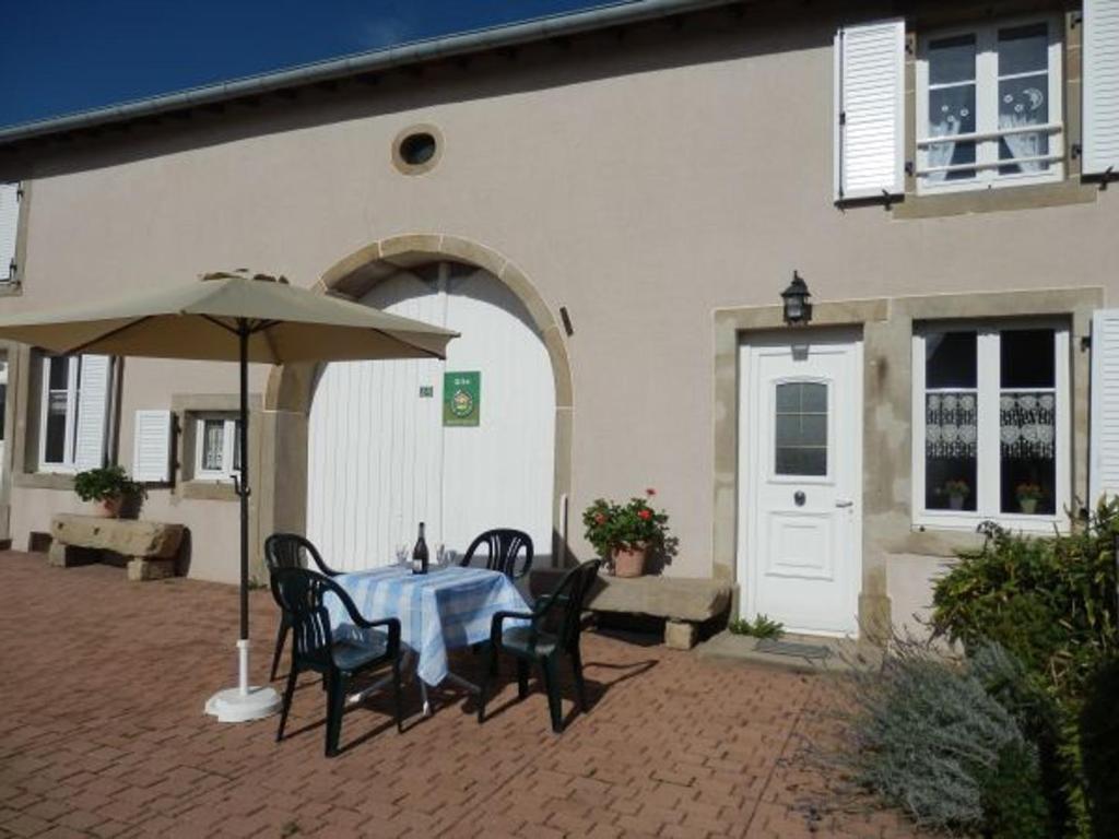 a table with chairs and an umbrella in front of a building at Gîte de Charme avec Terrasse près de Bourbonne-les-Bains, 2 chambres, poêle à bois, Wifi inclus - FR-1-589-118 in Lironcourt
