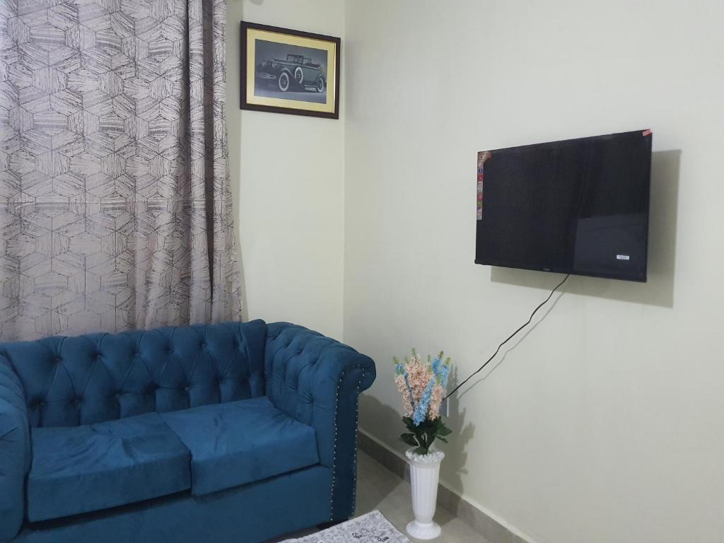 een woonkamer met een blauwe bank en een flatscreen-tv bij Regional Homes in Syokimau