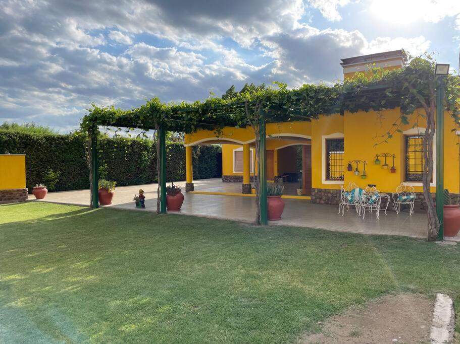 Casa amarilla con patio con mesas y sillas en Yellow House en Tunuyán