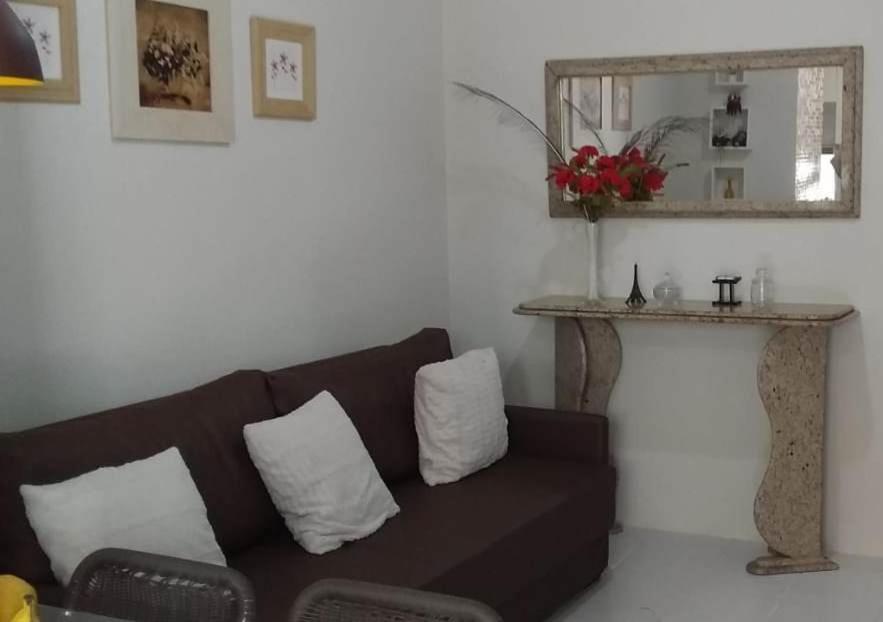 a living room with a brown couch and a mirror at Flat Condomínio Hotel Fazenda Gravatá Monte Castelo in Gravatá