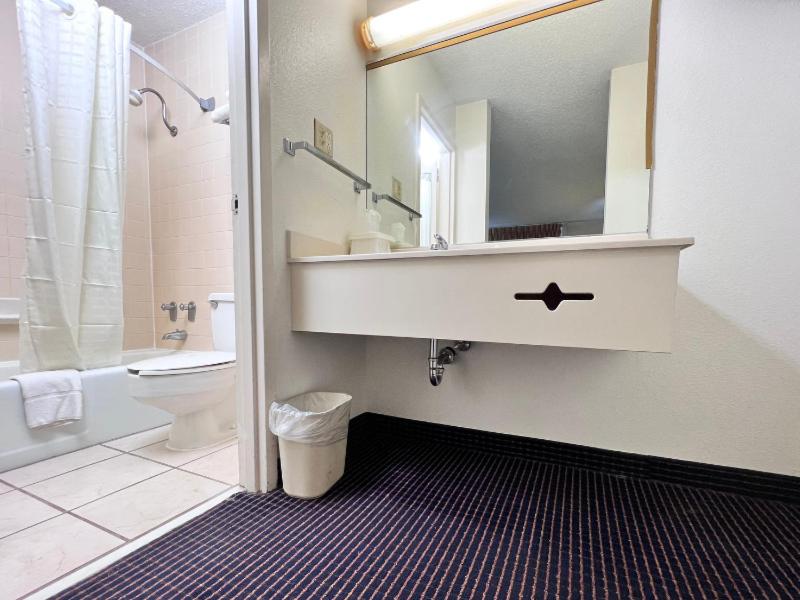 a bathroom with a sink and a toilet and a mirror at Heritage Inn and Suites in Baton Rouge