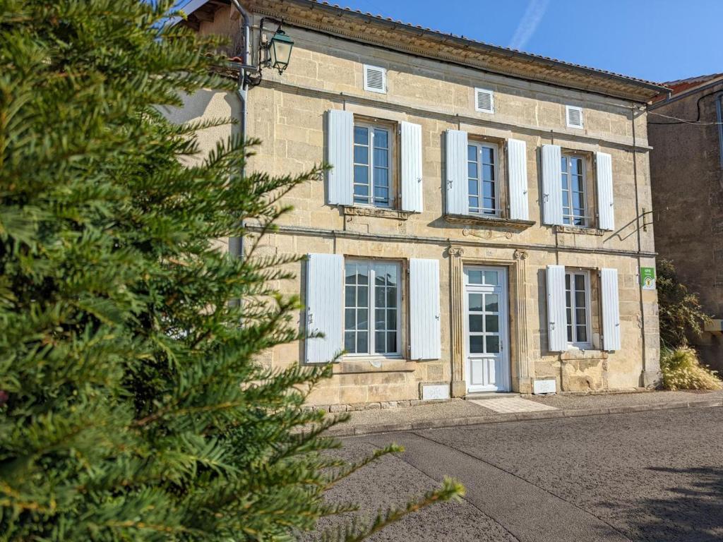 um edifício com janelas azuis e uma árvore em frente em Gîte Baignes-Sainte-Radegonde, 5 pièces, 7 personnes - FR-1-653-169 em Le Tâtre