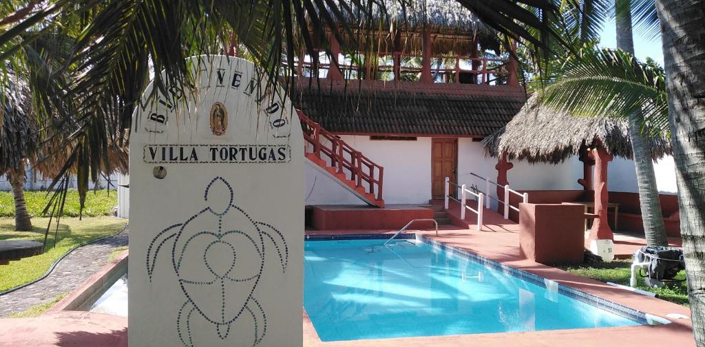 un cartel frente a un complejo con piscina en Villa Tortugas en Monterrico