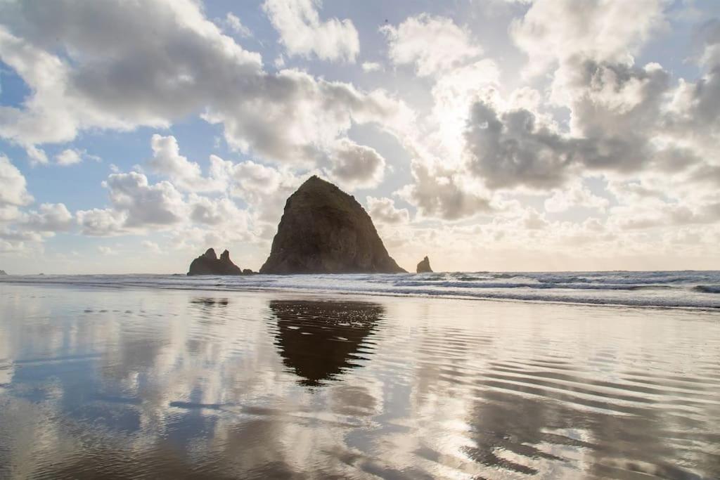 a rock formation in the ocean next to a beach at Cannon beach vibes, steps to the beach,WIFI,3 full bedroom en suites with 3 fireplaces,Near Downtown in Cannon Beach