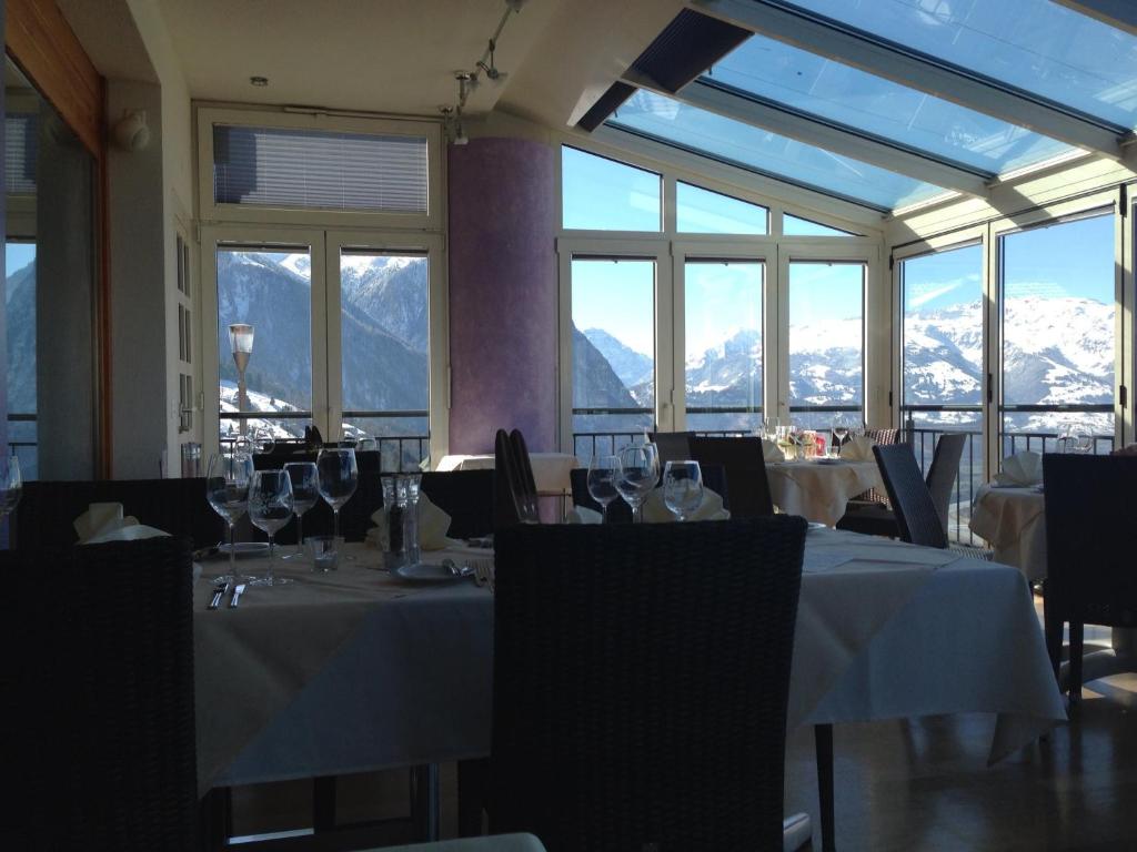 um restaurante com mesas e cadeiras com montanhas ao fundo em Hotel Restaurant Kulm em Triesenberg