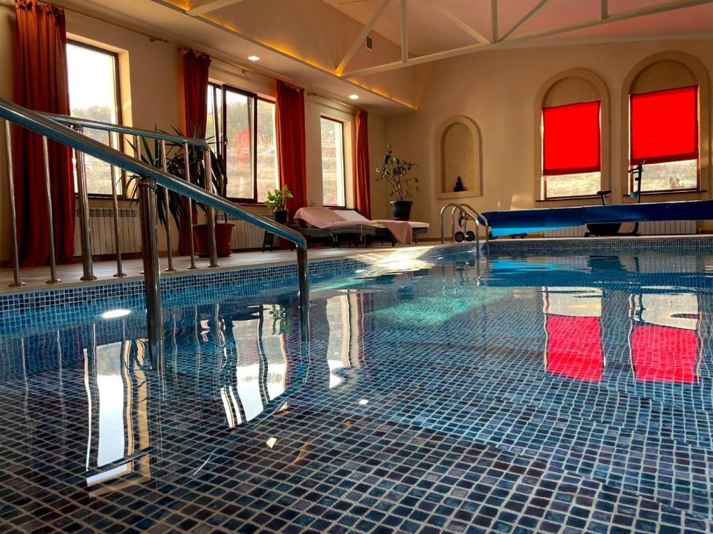 a large swimming pool in a building with red windows at Mountain Garden & SPA in Besqaynar