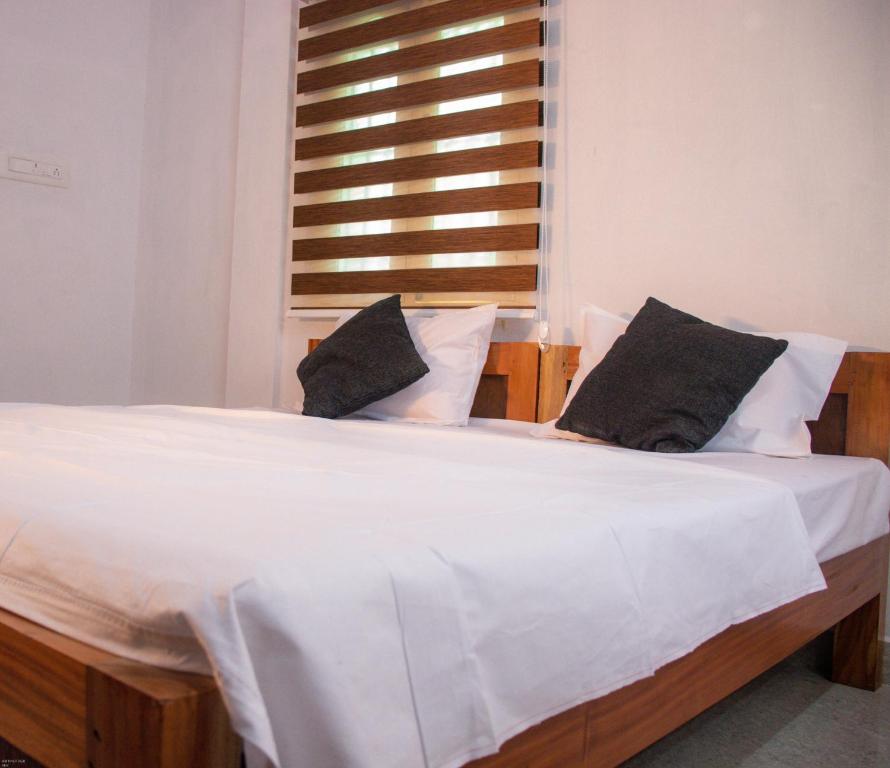 ein großes Bett mit weißer Bettwäsche und schwarzen Kissen in der Unterkunft Hotel Padma Shree , Madurai - Near Airport in Madurai