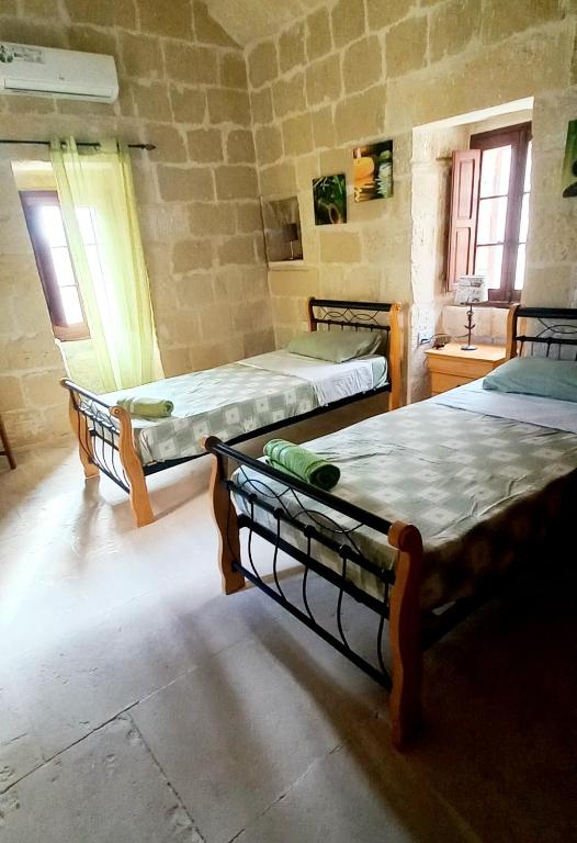 a room with three beds in a stone walled room at Ta Majsi farmhouse with indoor heated pool in San Lawrenz