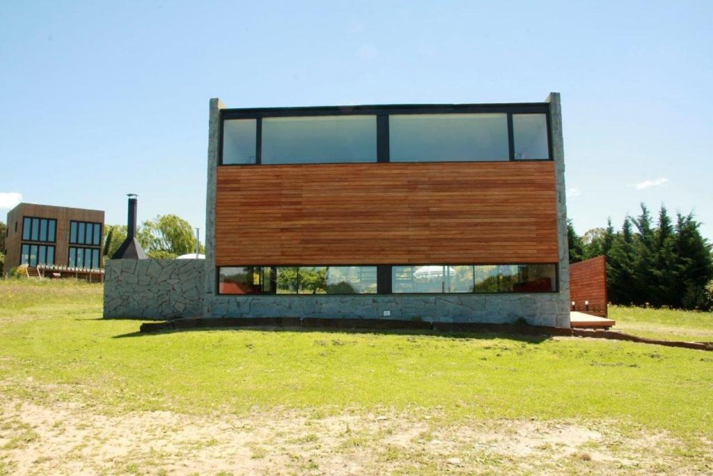 una casa en un campo de hierba con un edificio en Hoyo 6 Rincón del Golf en Sierra de la Ventana