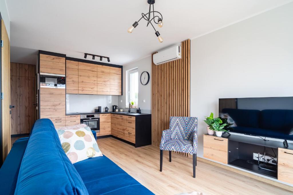 ein Wohnzimmer mit einem blauen Sofa und einer Küche in der Unterkunft Baltic Sun Muszelka in Sztutowo