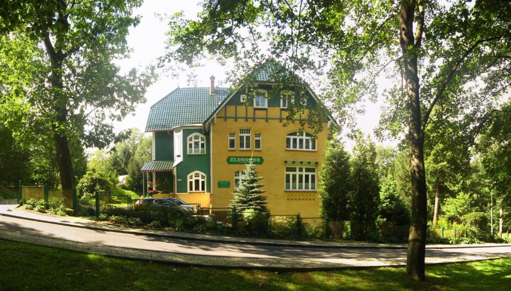 una gran casa amarilla con techo verde en Pensjonat Eldorado, en Świeradów-Zdrój