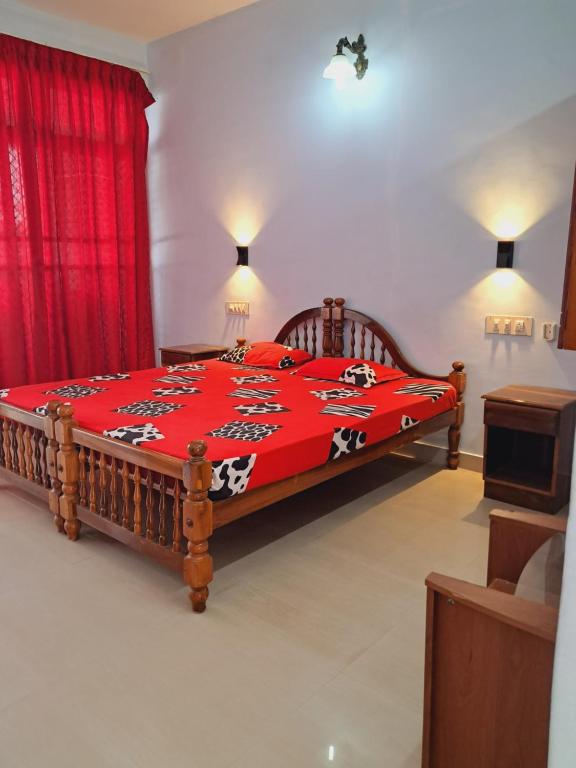 a bedroom with a wooden bed with a red blanket at Anamika Holiday home in Trivandrum