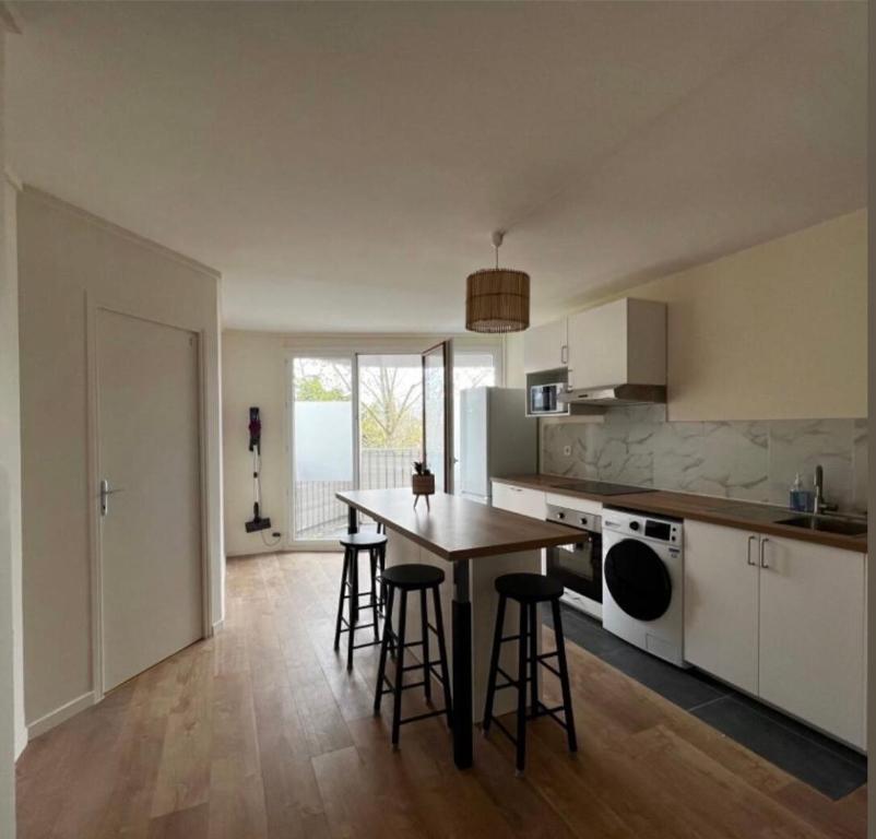 - une cuisine avec une table et des tabourets de bar dans l'établissement Chambres individuelles proche Orly longjumeau Massy, à Longjumeau