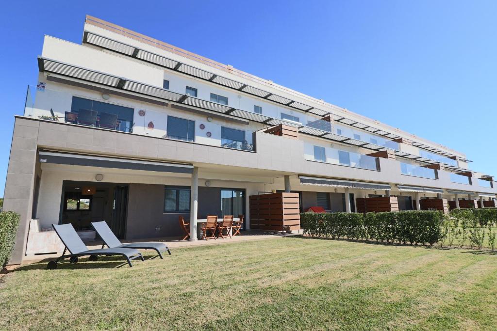 un gran edificio con 2 sillas en un patio en Apartamento Familiar La Reserva, en El Rompido