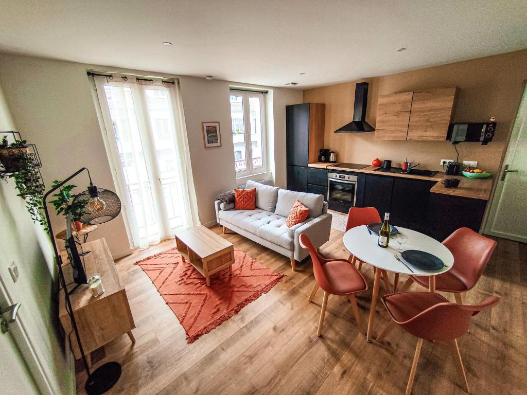 een woonkamer met een bank en een tafel bij Nouveau T2 en face du lac - Meublé tourisme - Garage privé in Évian-les-Bains