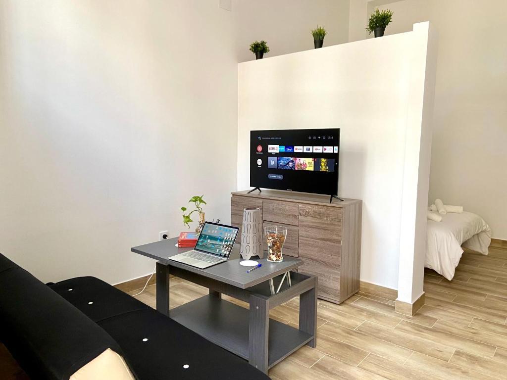 - un salon avec un canapé et une table avec un ordinateur portable dans l'établissement Apartamentos cruz roja B, à Séville