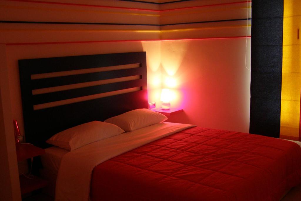 a bedroom with a bed with a red blanket and a light at Room in a neoclassical house - ladybug in Kastoria