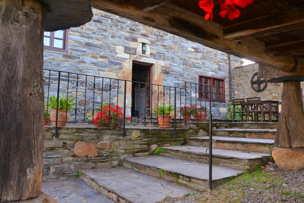 a stone building with stairs and a gate with flowers at Apartamentos Rurales RON in Ron